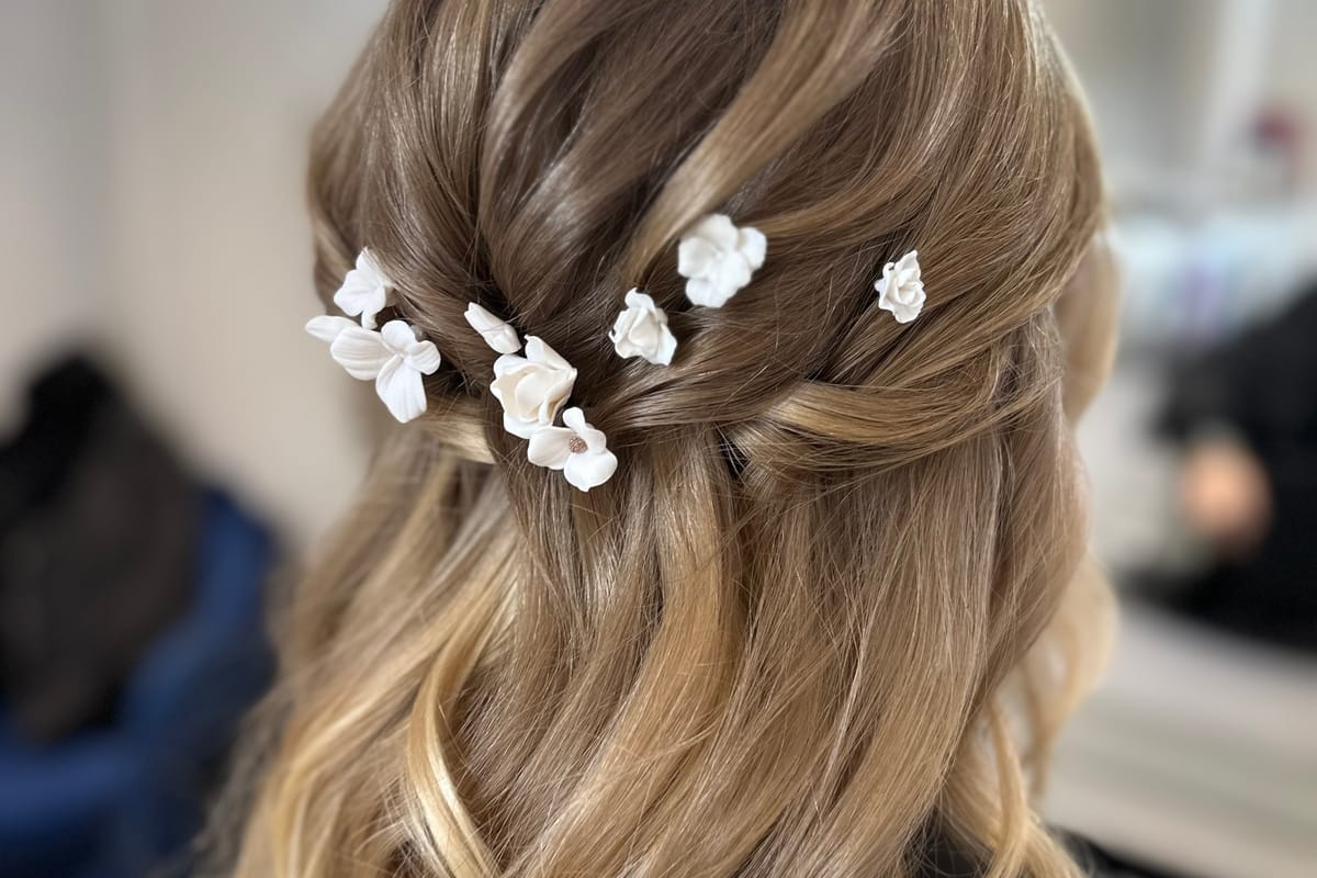 White porcelain flower hair pins arranged through a half-up bridal hairstyle